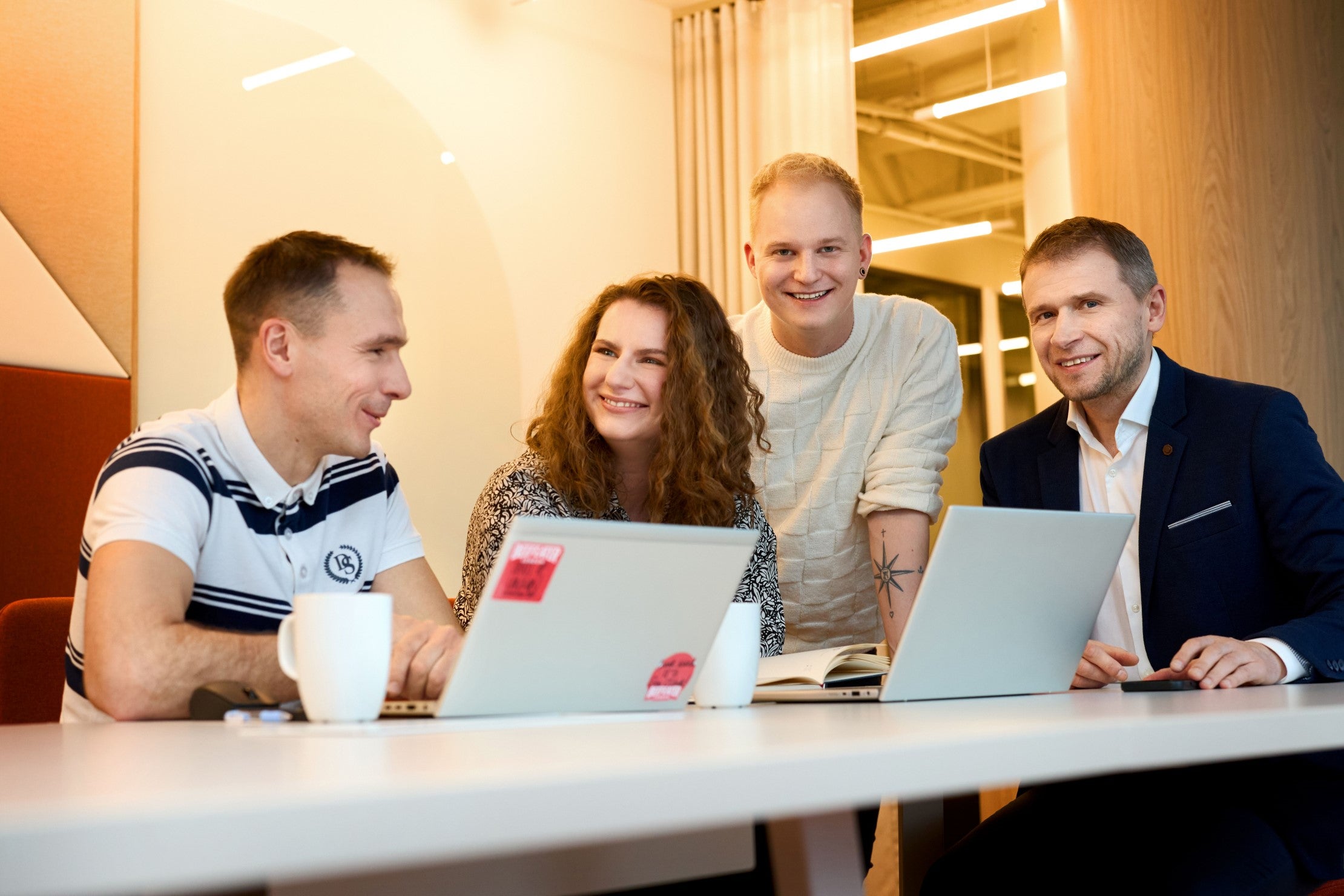 trzech mężczyzn i kobieta współpracują przy laptopach