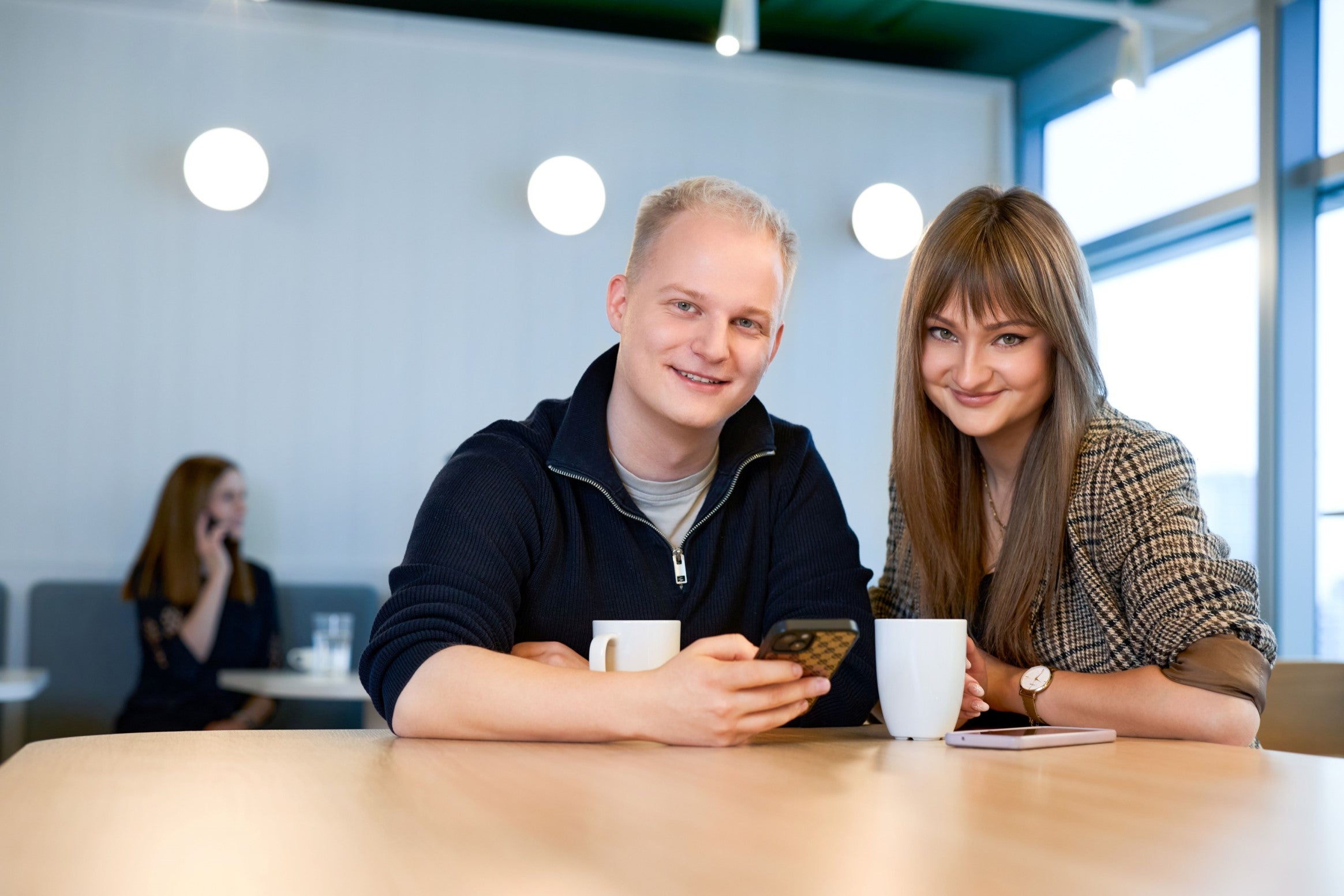 Młody mężczyzna i młoda kobieta uśmiechają się, siedzą przy stole
