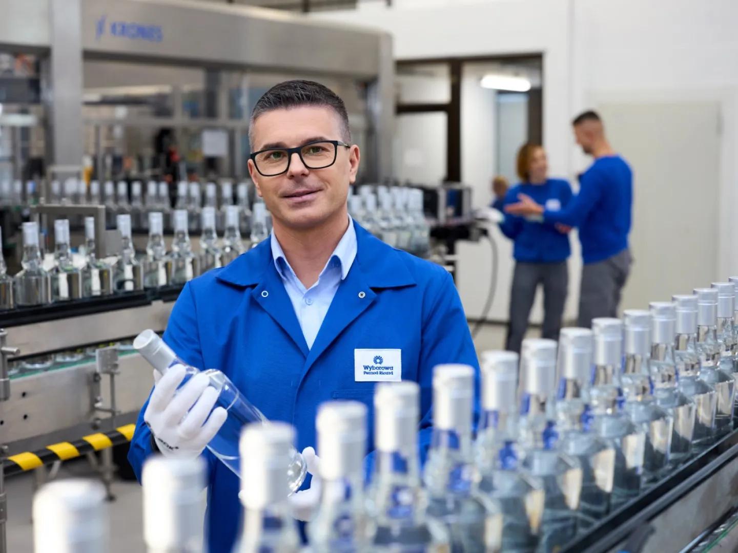 Mężczyzna przy taśmie produkcyjnej z butelkami