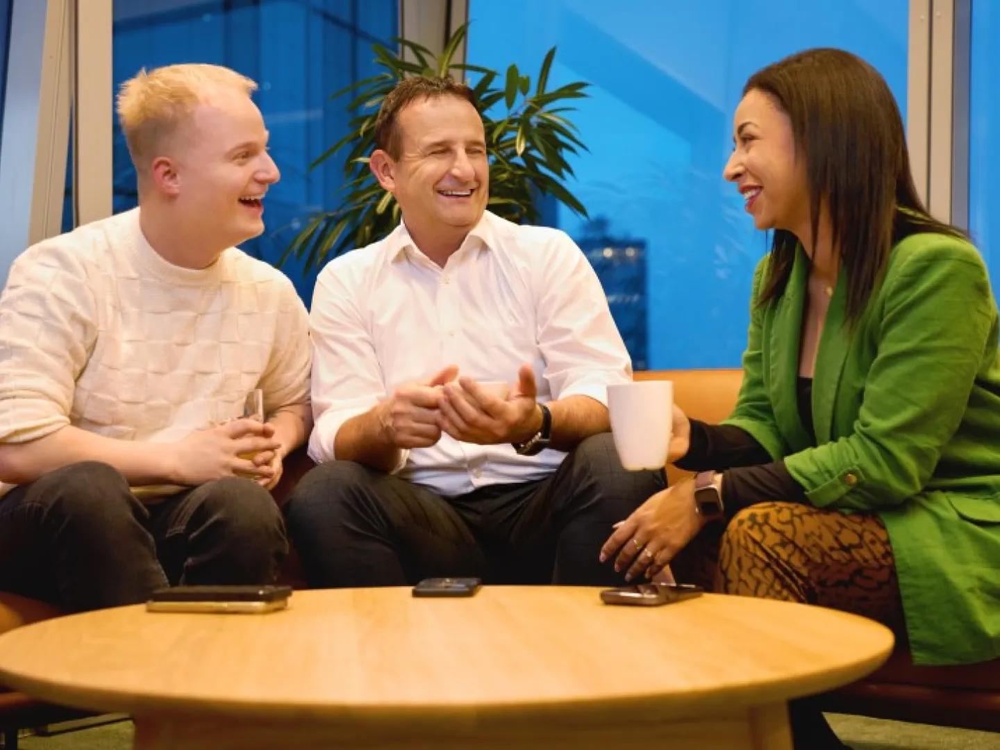 two men and a woman talking at a coffee table