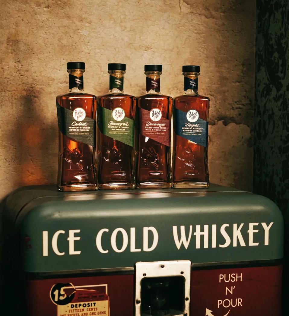 Four bottles of Rabbit Hole Whiskey arranged on a vintage vending machine.