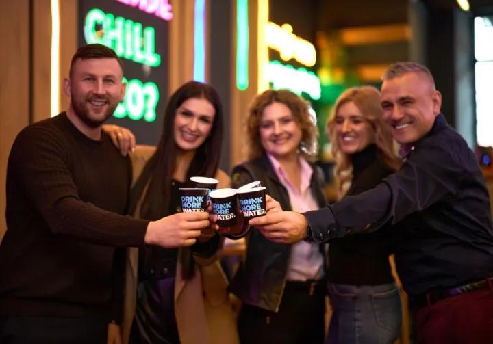 two men and two women toast with cups of Drink more water