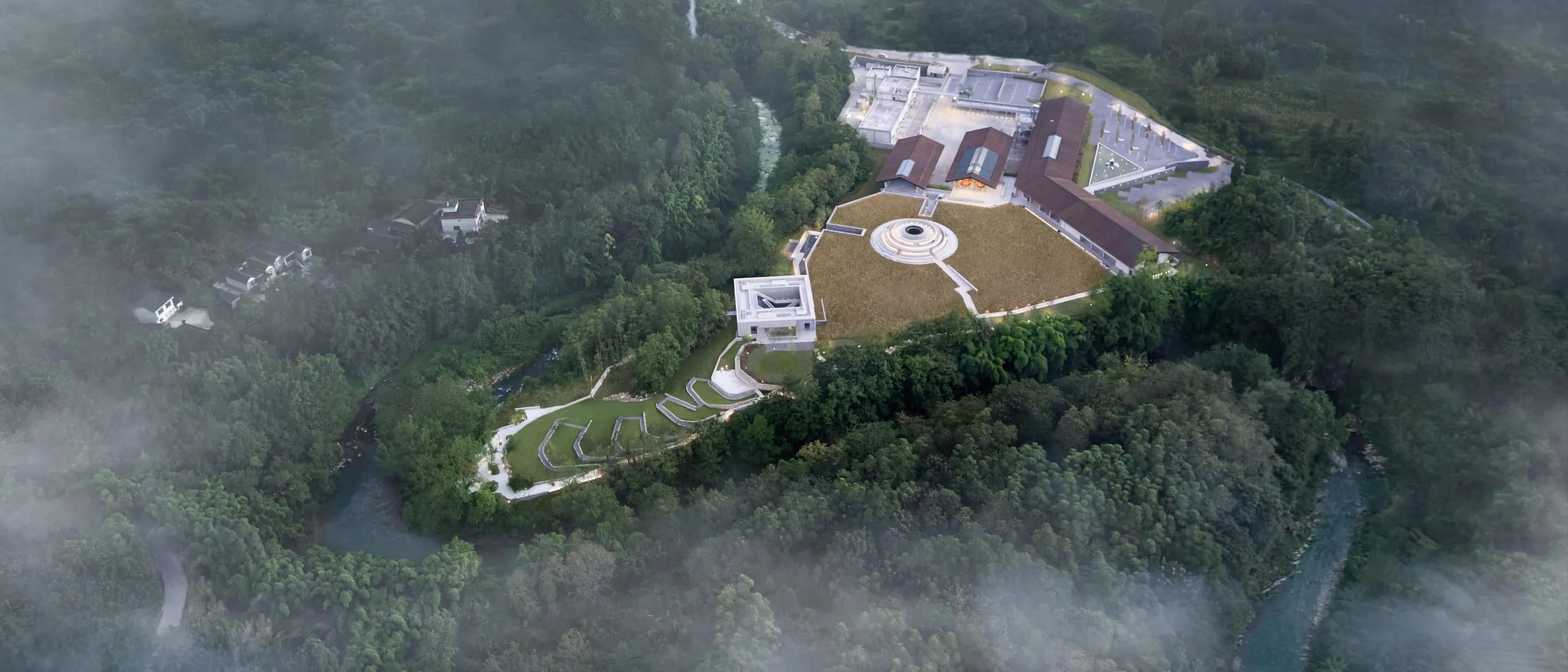 Aerial view of The Chuan distillery with surrounding forests and clouds