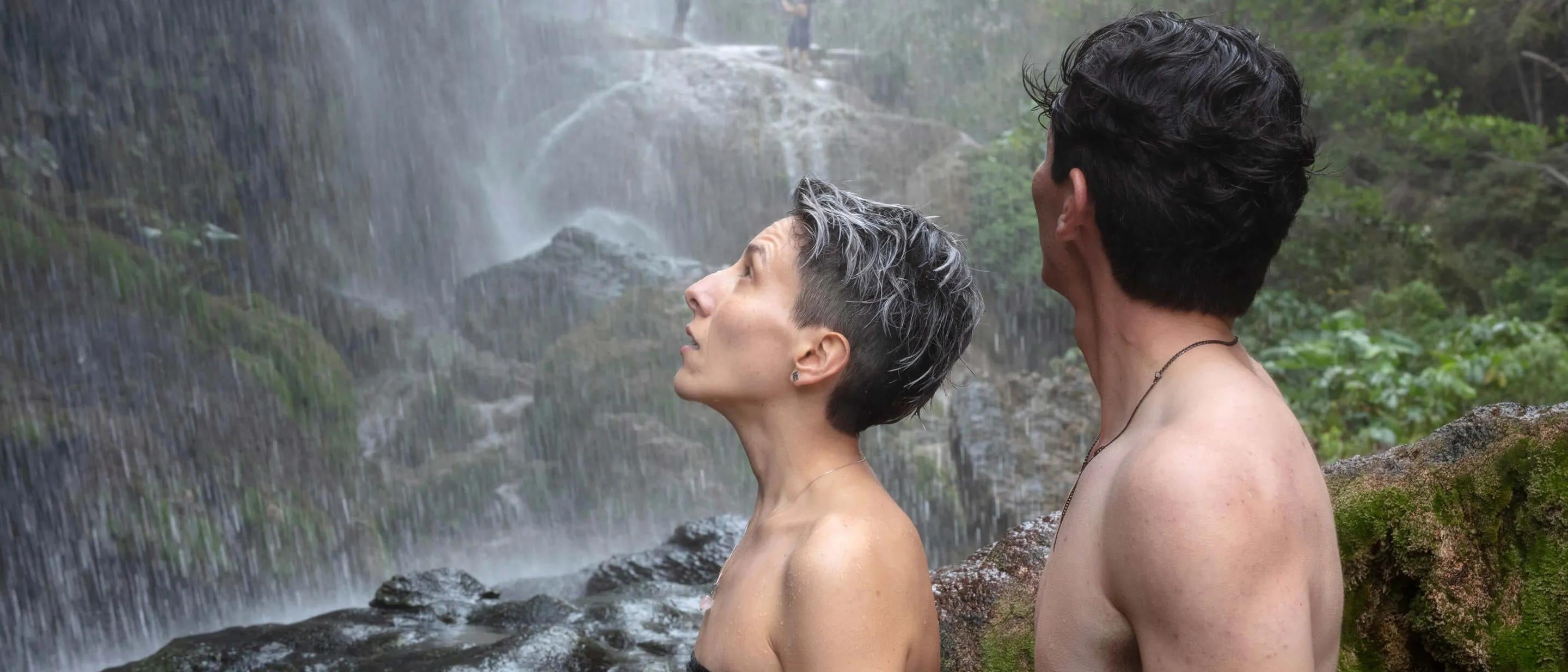 Two people side-on in front of a waterfall