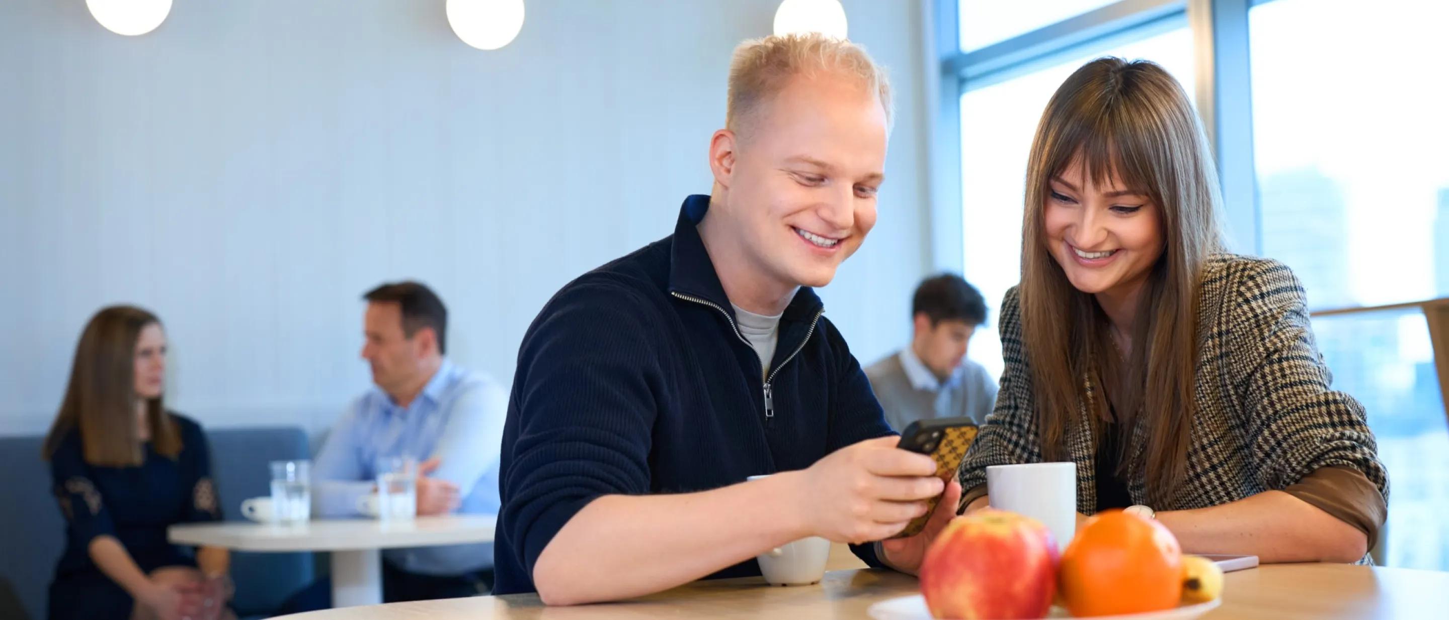 a man and a woman talking over coffee and looking at a mobile